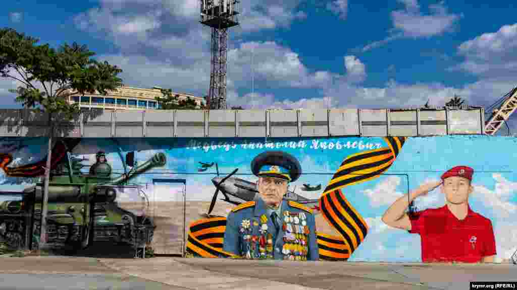 Территорию вокзала от набережной имени Ленина отделяет каменный забор, украшенный новыми муралами. Им предшествовал, начиная с 2014 года, мурал с российским президентом Путиным на фоне современного военного самолета  