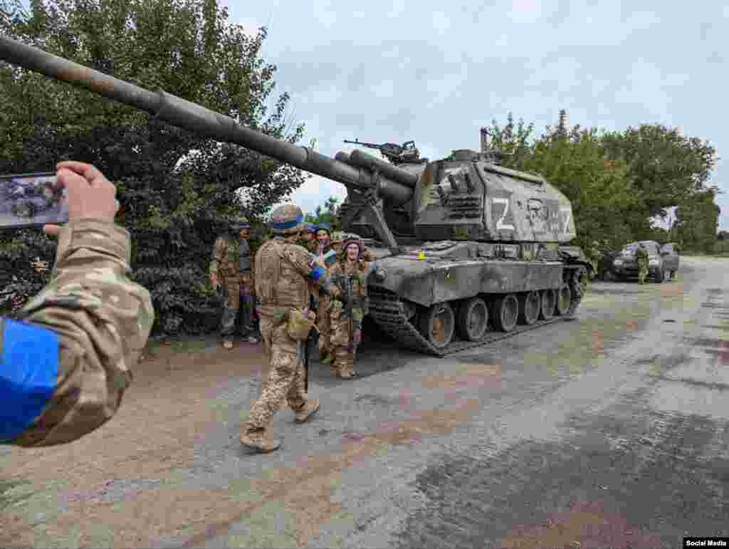 Українські війська збираються для колективного фото біля трофейної 2С19 «Мста», яку російська армія покинула під час хаотичного відступу.  Самохідні гаубиці є одними з найпотужніших артилерійських знарядь Росії. Їхня вартість близько 1,5 мільйона доларів за одиницю