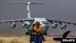 A Taliban fighters sits guard in the backdrop of a Russian plane transporting aid relief donated by Russia for the Afghan people, at Kabul Airport on November 18.