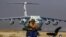 A Taliban fighters sits guard in the backdrop of a Russian plane transporting aid relief donated by Russia for the Afghan people, at Kabul Airport on November 18. 