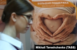 Žena prolazi pored plakata na događaju za mlade roditelje u Moskvi 2018. godine.