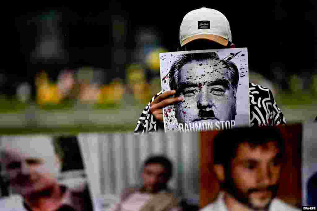 Молодой человек держит плакат "Стоп Рахмон", протестуя против приезда президента Таджикистана Эмомали Рахмона в Германию. Рахмон приехал на встречу канцлера Германии с лидерами пяти стран Центральной Азии. Берлин, 29 сентября 2023 года