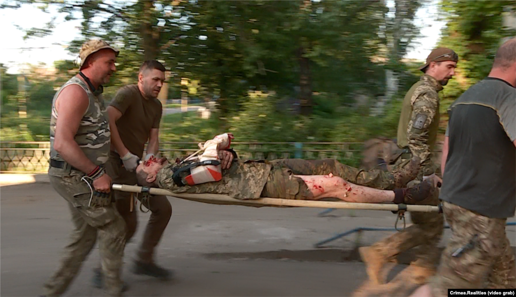 Після чергового важкого бою з російськими військами на південному напрямку до стабпункту привезли поранених бійців ЗСУ. На фото: медики стабпункту несуть на ношах важкопораненого бійця. Кінець липня 2023 року. На початку контрнаступу в стабілізаційний пункт із передової привозили  до сотні поранених на день. Їх стабілізували і транспортували далі – в лікарню