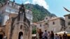 Kotor - Tourists stand in front of a church as they visit the medieval city of Kotor on August 21, 2018. 