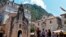 Kotor - Tourists stand in front of a church as they visit the medieval city of Kotor on August 21, 2018.