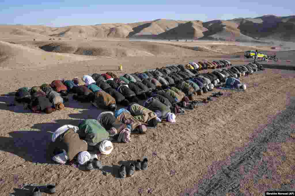 Afghans pray for relatives who were killed in an earthquake at a burial site in Zindah Jan. The rugged area is difficult to reach, and local officials have given conflicting casualty tolls from the series of quakes in the area. On October 8, a member of the Taliban-led government said the updated death toll had surpassed 2,000.