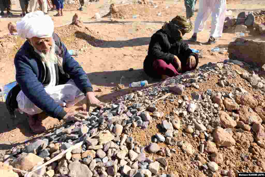 Mourners sit beside graves after funeral prayers for their relatives. In addition to the WFP, teams from the UN's World Health Organization (WHO) have rushed to the areas of Herat worst affected by the quakes. WHO employees are already in the field helping with efforts to rescue and treat people still under the rubble, the organization's Afghan branch told RFE/RL.