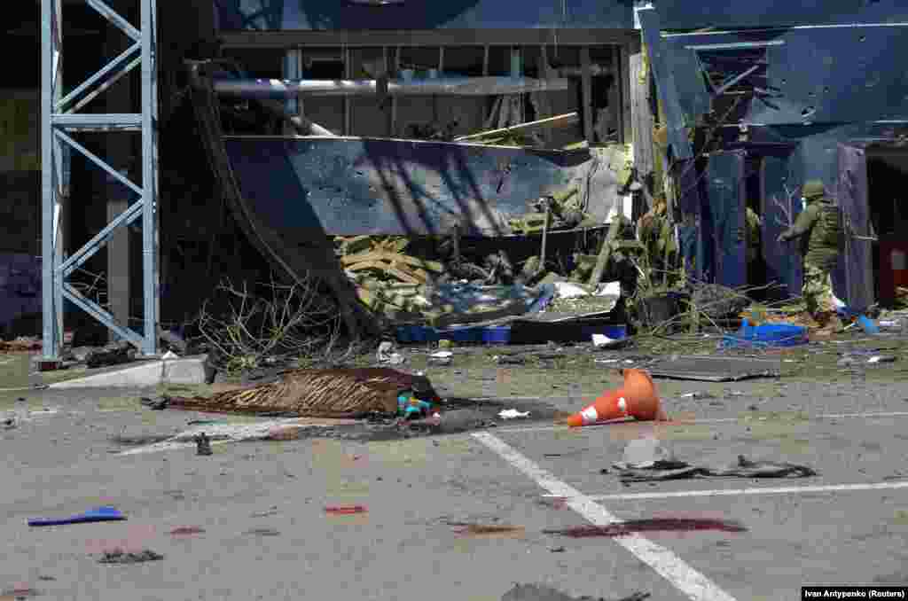 The body of another victim covered by a blanket is seen outside a shopping center. Ukrainian troops recaptured Kherson last November after nearly eight months of Russian occupation. The area is now under almost daily bombardment from Russian forces entrenched on the opposite side of the Dnipro River.