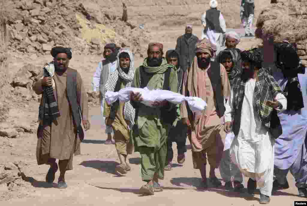 A man carries the lifeless body of his child, who was killed during an earthquake in the village of Sarbuland in Herat Province's Zindah Jan district on October 8. Aid workers have reached some quake-stricken areas of western Afghanistan and started distributing emergency food supplies to those affected as rescue efforts continued after a series of powerful temblors killed at least 2,000 people.