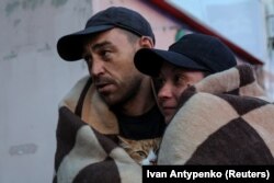 Чоловік і жінка несуть кота під час евакуації із затопленої території після пошкодження дамби Каховської ГЕС, Херсон, 6 червня 2023 року