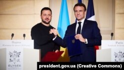 Президент України Володимир Зеленський і президент Франції Емманюель Макрон (праворуч) демонструють підписану Угоду про співробітництво у сфері безпеки між Україною та Францією. Париж, 16 лютого 2024 року