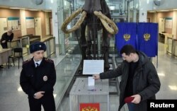 A police officer watches a man cast a ballot at a polling station at Novosibirsk State University in Novosibirsk, Russia, on March 17.