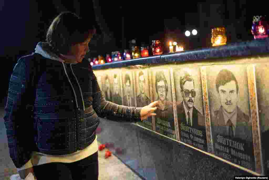 Жінка торкається фото на меморіалі пожежникам та працівникам ЧАЕС, жертвам аварії 1986 року, Славутич, 26 квітня 2023 року  