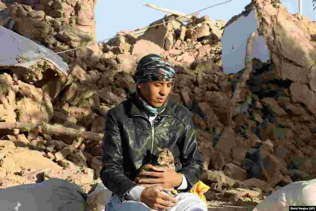  An Afghan youth holds his cat as he sits in a courtyard of his destroyed home. Mullah Janan Sayeeq, a spokesman for the Taliban's Ministry of Disasters, told a news conference that 2,440 people were dead, about 10,000 were injured, and that more than 2,000 houses had been damaged or destroyed. Afghanistan's disaster agency said on October 8 that 2,053 people had been killed. Neither estimate could be independently confirmed.