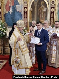 George Simion, leaderul AUR, primind Crucea Șaguniană de la Mitropolitul Ardealului.