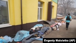 Полицейский идет вдоль тел людей, погибших во время обстрела Мариуполя, 15 марта 2022 года