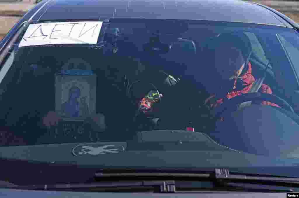 Mariupol residents try to leave the city by car, and one person holds a Christian icon for protection. The sign in the window says: "Children."