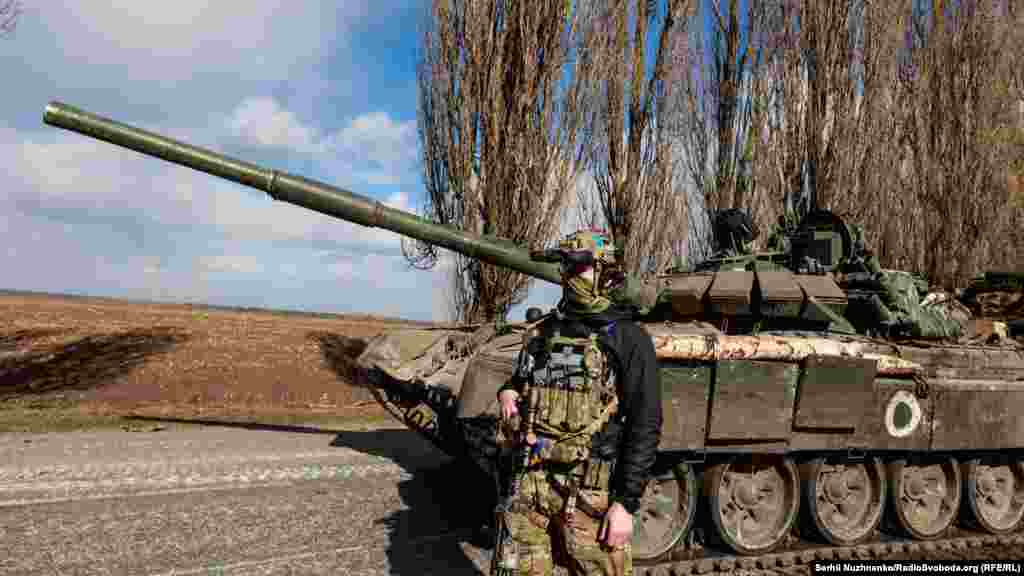 Український військовий  стоїть поруч із захопленим  у бою російським танком  Т-72 