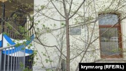 Табличку закрывает дерево, выросшее в последние годы в метре от стены здания