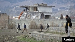 Policemen walk past as demolition work continues on February 26 on the building where Al-Qaeda leader Osama bin Laden was killed by U.S. special forces in May 2011.