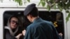 An Iranian morality policeman speaks with a woman siting in a police vehicle after she was arrested for failing to observe the mandatory Islamic dress code. (file photo)