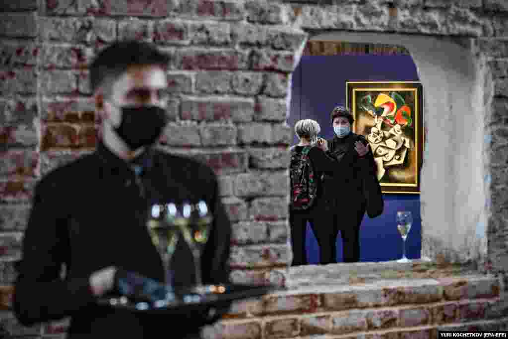 Посетители беседуют у картины «Мальчик с воздушными шариками» российского художника Олега Целкова во время предаукционной выставки Sotheby's избранных произведений русских художников XIX и XX веков в Государственном музее архитектуры в Москве