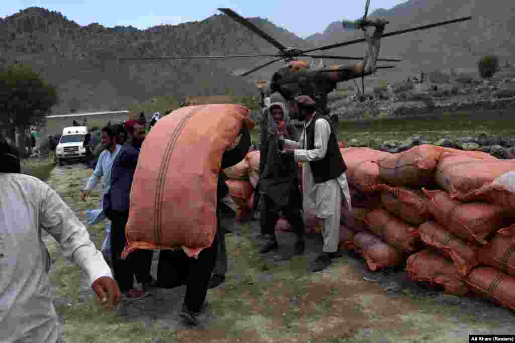 Afghan men stack sacks of aid in Gayan. 