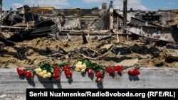 Цветы у развалин ТЦ в Кременчуге, уничтоженного ударом российской крылатой ракеты