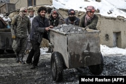 Workers push a cart filled with raw stones before sorting for emeralds.