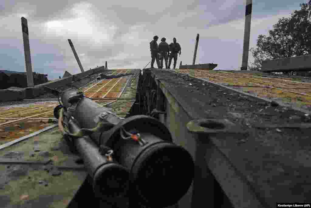 Українські військовослужбовці стоять на зруйнованому мосту через річку Сіверський Донець в Ізюмі, 13 вересня. Втрата контролю над містом Ізюм вважається стратегічною невдачею для Москви, оскільки її війська використовували місто як базу та маршрут постачання для своїх сил в Україні  