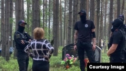 Люди в черном окружили женщину, пришедшую на акцию памяти в Сандармохе