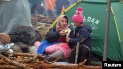 A migrant and her children rest beside a tent in Belarus's Hrodno region, near the Polish border, on November 10.