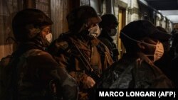 سربازان و نیروی پلیس آفریقای جنوبی در حالی که به دلیل شیوع کرونا ماسک زدهاند در حال جستوجوی ساختمانی در جریان ممنوعیتهای رفتوآمد هستند.