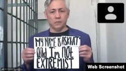 Асхат Жексебаев сотта "менің атым Асхат және мен экстремист емеспін" деген жазуы бар плакат ұстап тұр. Қыркүйек 2021 жыл.
