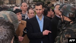 Syrian President Bashar al-Assad (center) speaks to soldiers during a tour of the restive Baba Amr neighborhood of Homs late last month.