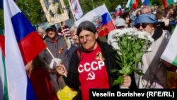 Жена с тениска с надпис "СССР", букет цветя и руско знаме участва в отбелязването на руския Ден на победата в София, 9 май 2025 г.