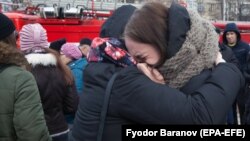 Two girls comfort each other as they cry near the site of a shopping-mall fire in the Siberian town of Kemerovo that left scores of people dead, many of them children.