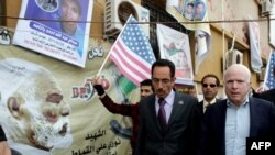 John McCain (right) walks with Abdul Hafiz Ghoqa, spokesman of the Libyan National Transitional Council, during his tour of the rebel headquarters in Benghazi