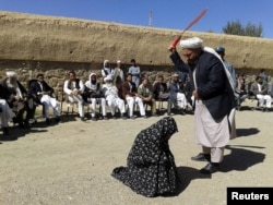An Afghan judge whips a woman in front of a crowd in Ghor Province.