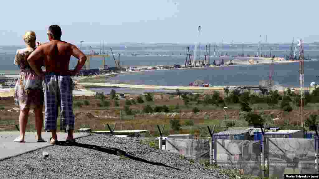 People near the Russian town of Taman look out in July 2016 over the construction of the Kerch bridge, snaking 19 kilometers toward Crimea. A crew of around 5,000 people are working around the clock on the project, which began in May 2015. 