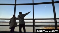 Посетители обзорной площадки на южнокорейской стороне у демилитаризованной зоны - рассматривают территорию Северной Кореи