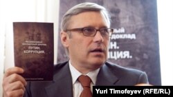 Former Prime Minister Mikhail Kasyanov holds up a copy of the report "Putin. Corruption," at its presentation on March 28.