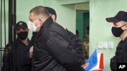 Bloggerul Serghie Țihanovski (centru) în fața cuștii în care va fi ținut în sala de judecată (fotografie de arhivă).