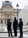 Полицейские стоят возле пирамиды музея Лувр после сообщения об ограблении в Париже, Франция, 19 октября 2025 года. REUTERS/Gonzalo Fuentes