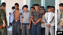 Police officers search detained ethnic Uzbeks in the village of Nariman on June 21