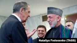 Russian Foreign Minister Sergei Lavrov (left) and former Afghan President Hamid Karzai talk at a meeting dedicated to the 100th anniversary of official Russian-Afghan diplomatic relations in Moscow on May 28.