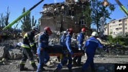 Українські рятувальники несуть тіло жертви, знайдене під час пошуково-рятувальної операції на місці житлового будинку, сильно пошкодженого внаслідок удару РФ в Києві, 28 серпня 2025 року