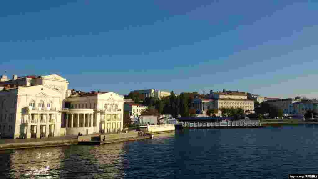 Зліва відкривається огляд на Приморський бульвар, зокрема, на Палац дитинства і юності, театр імені Луначарського, готель «Севастополь»