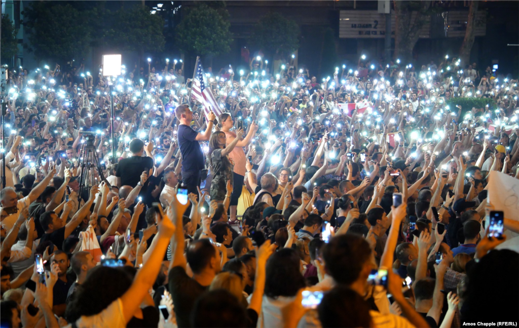Demonstrators hold their cellphones in the air as the Georgian national anthem is sung. 
