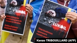 Снимката е илюстративна. Протестиращи държат плакати с искания за санкции срещу руската компания "Лукойл" в Брюксел, 13 май 2022 г.